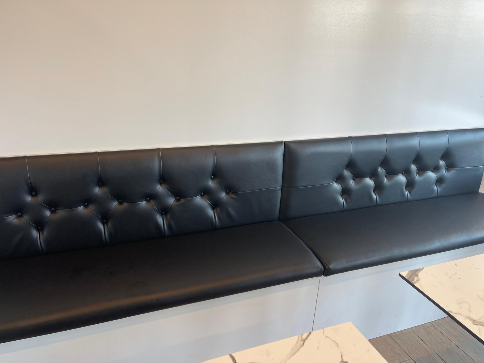 Black tufted bench against white wall