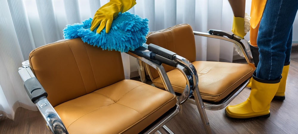 Person cleaning brown chairs with cloth