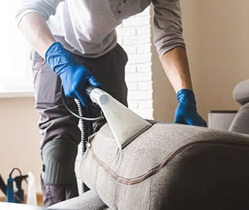 Person cleaning sofa with vacuum
