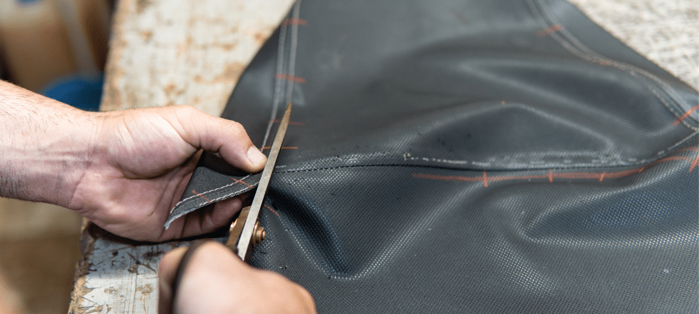 Person cutting black leather material.