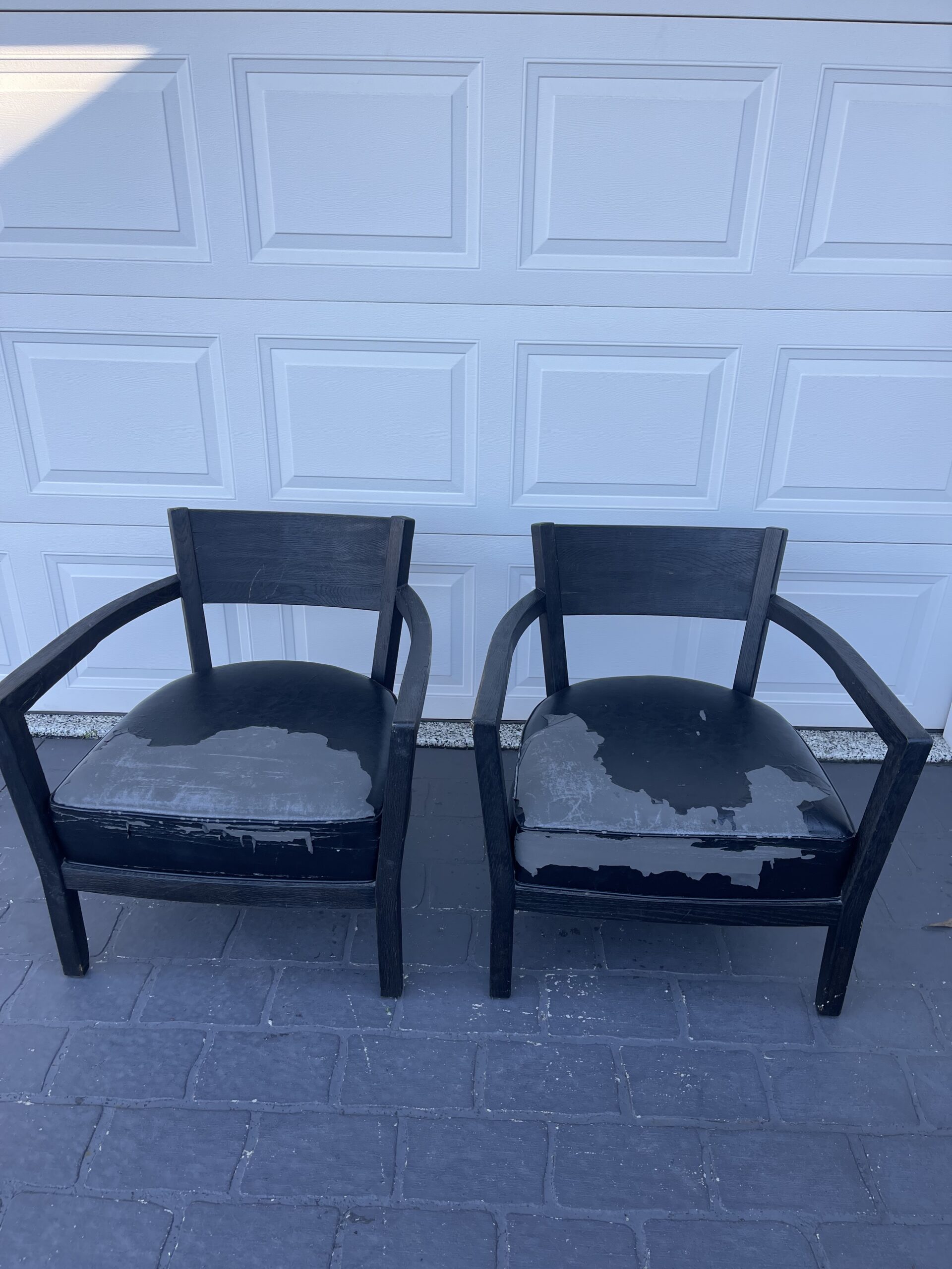 Two worn black chairs side by side