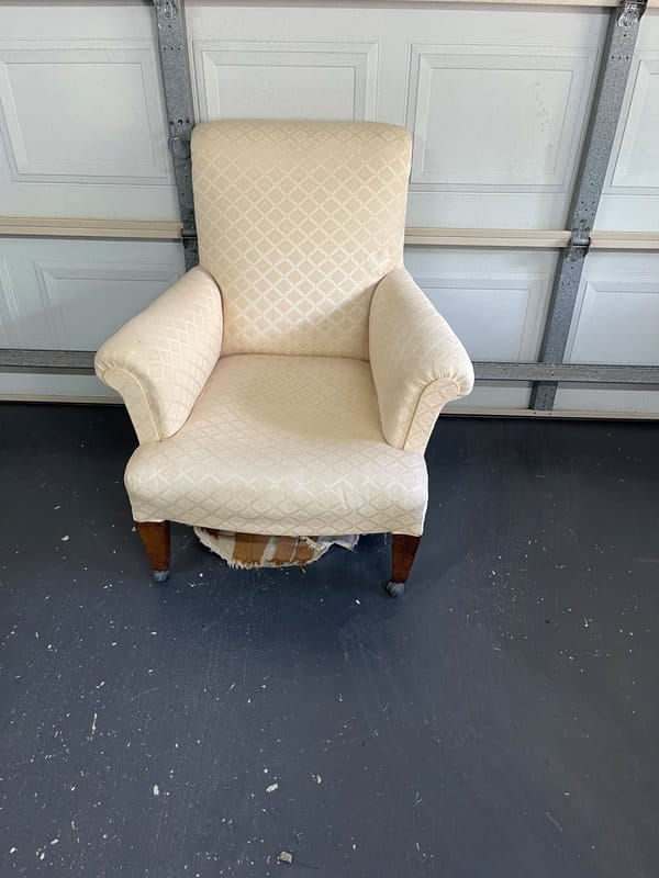 Worn beige chair with exposed fabric