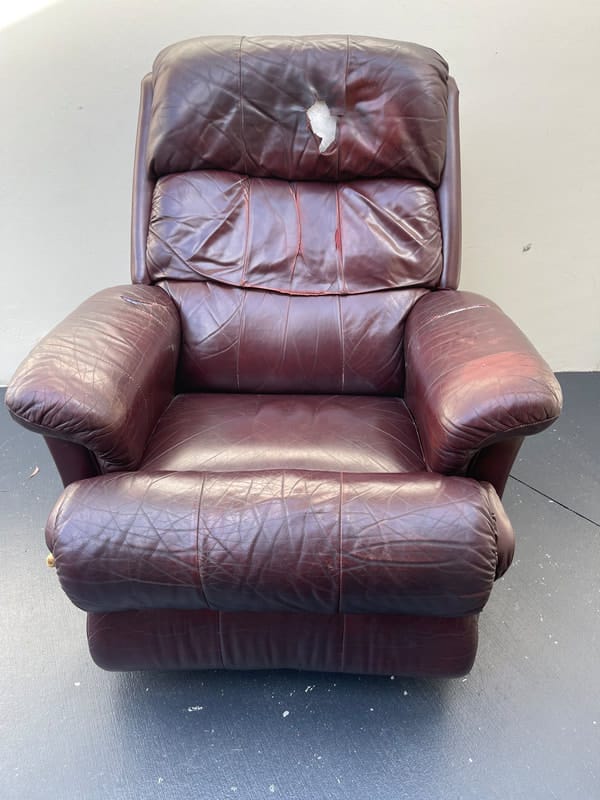 Worn leather recliner with damage